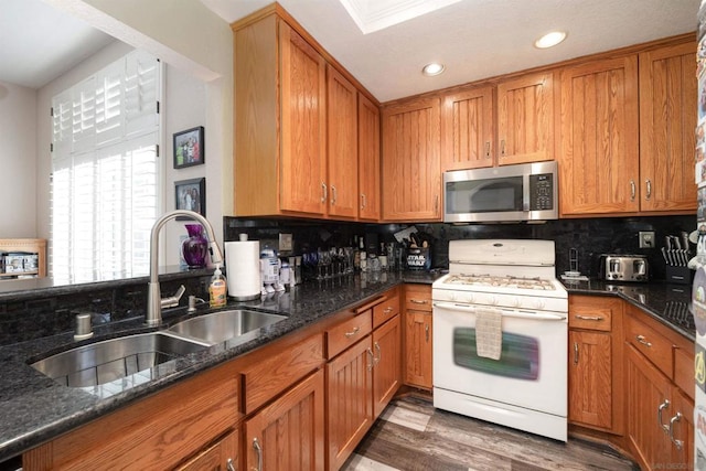 kitchen with tasteful backsplash, sink, dark stone counters, white gas range, and dark hardwood / wood-style flooring