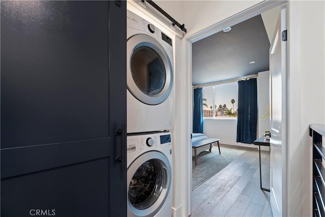 washroom with stacked washer / dryer and light hardwood / wood-style flooring