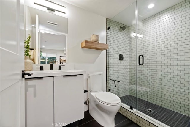 bathroom featuring tile patterned flooring, vanity, toilet, and walk in shower