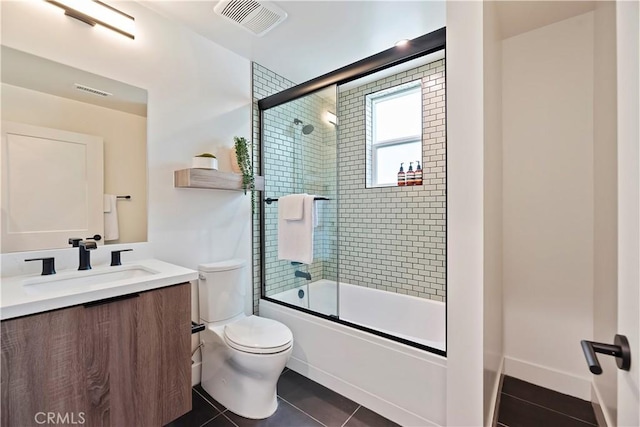 full bathroom featuring toilet, vanity, tile patterned floors, and enclosed tub / shower combo