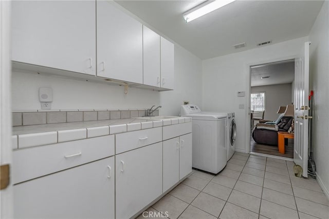 clothes washing area with cabinets, light tile patterned floors, separate washer and dryer, and sink