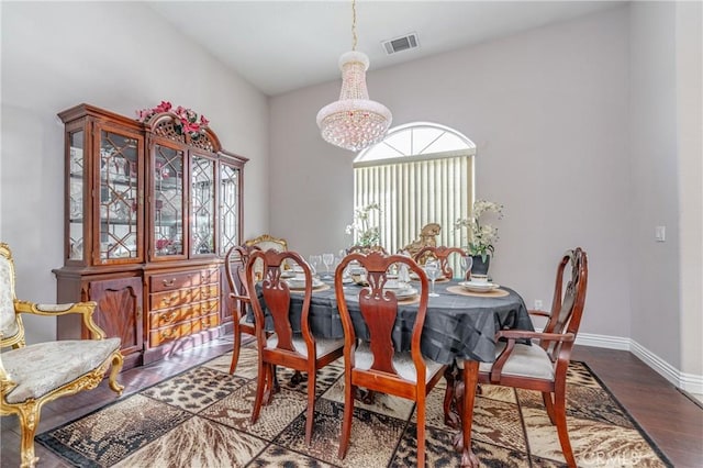 dining room with vaulted ceiling, dark wood-type flooring, and an inviting chandelier