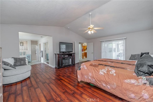 bedroom with ceiling fan, a fireplace, dark wood-type flooring, and vaulted ceiling