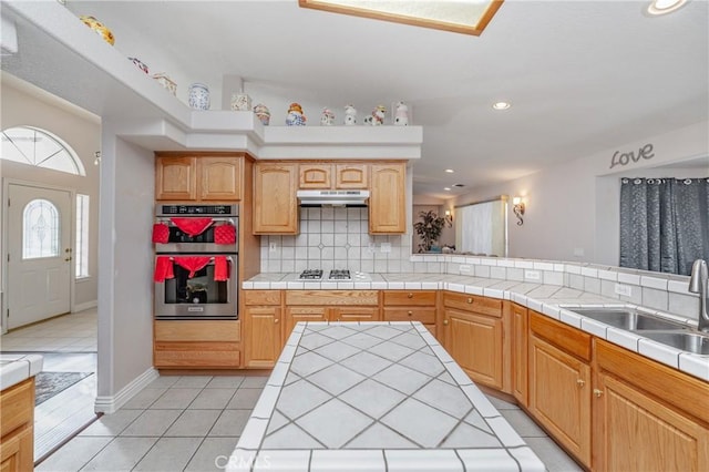 kitchen with sink, tasteful backsplash, double oven, tile countertops, and light tile patterned flooring