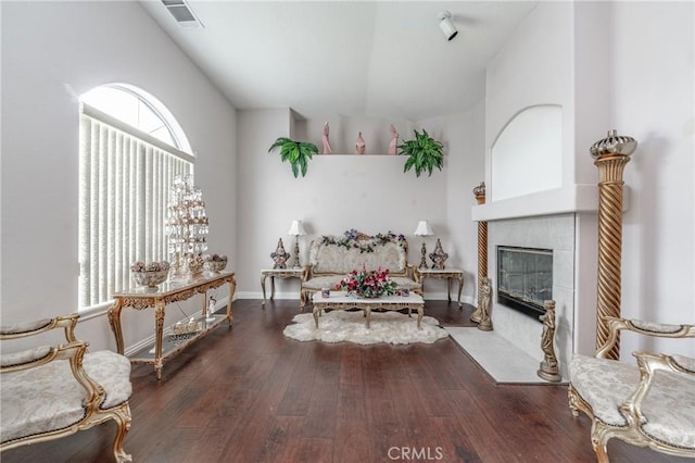 living area featuring dark wood-type flooring, high vaulted ceiling, and a tiled fireplace