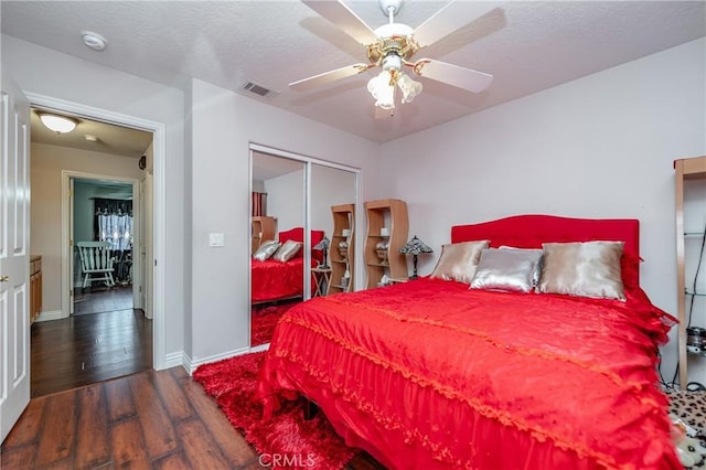 bedroom with a textured ceiling, a closet, dark hardwood / wood-style floors, and ceiling fan