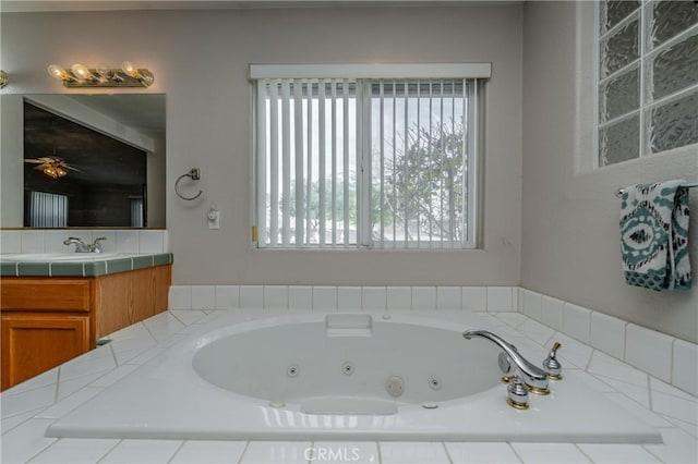 bathroom with vanity, ceiling fan, and tiled tub