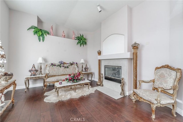 living area with a tile fireplace, lofted ceiling, and hardwood / wood-style flooring