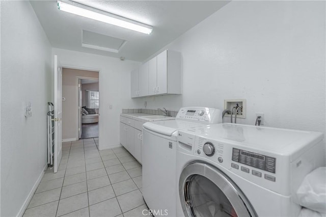 washroom with washing machine and dryer, sink, light tile patterned floors, and cabinets