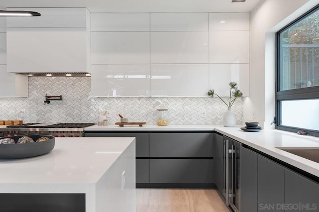 kitchen with tasteful backsplash, white cabinetry, sink, and stainless steel gas cooktop