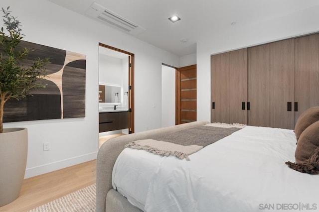 bedroom featuring ensuite bathroom and light wood-type flooring