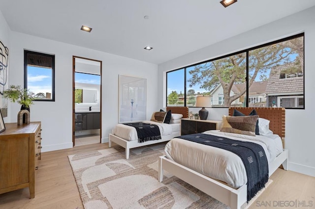 bedroom with ensuite bathroom and light hardwood / wood-style floors