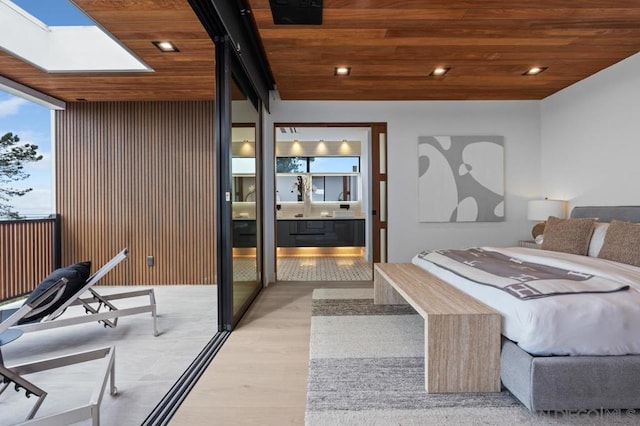 bedroom featuring light wood-type flooring, a skylight, a wall of windows, and wooden ceiling