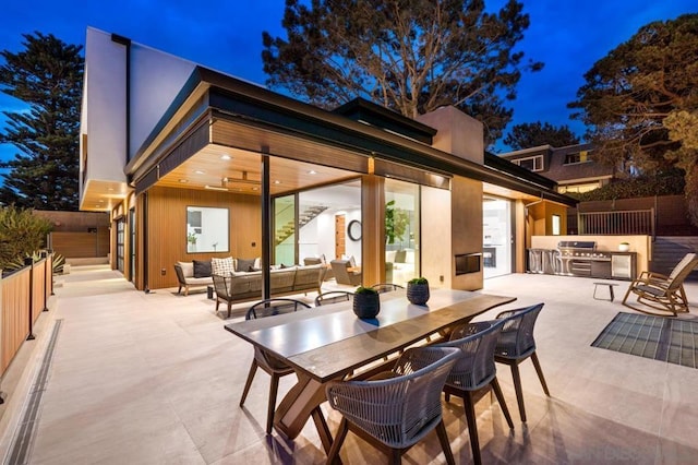 patio at night with an outdoor kitchen, a grill, and an outdoor hangout area