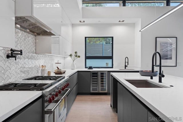 kitchen with gray cabinetry, sink, high end range, and beverage cooler