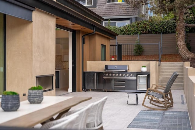 view of patio / terrace featuring a fireplace, an outdoor kitchen, and a grill