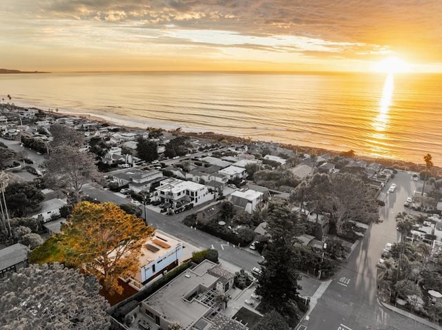 aerial view at dusk with a water view and a view of the beach