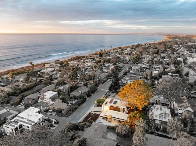 aerial view at dusk with a view of the beach and a water view