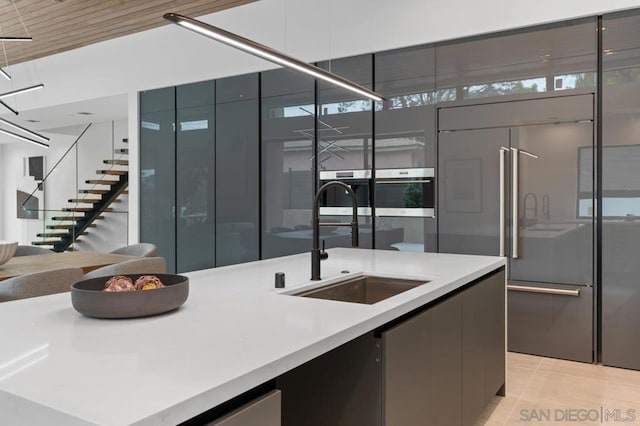 kitchen featuring light tile patterned floors, paneled refrigerator, and sink