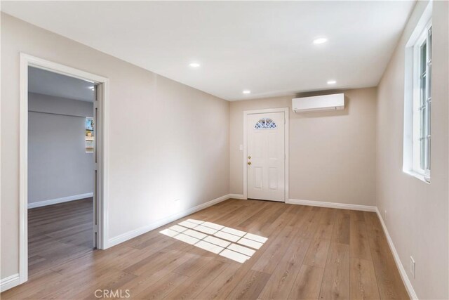 foyer entrance with light hardwood / wood-style floors and a wall unit AC