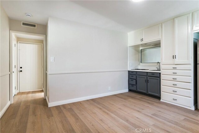 kitchen featuring light wood-type flooring, gray cabinets, white cabinetry, and sink