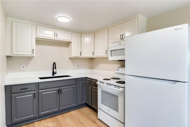 kitchen featuring white appliances, sink, light hardwood / wood-style flooring, gray cabinets, and white cabinetry