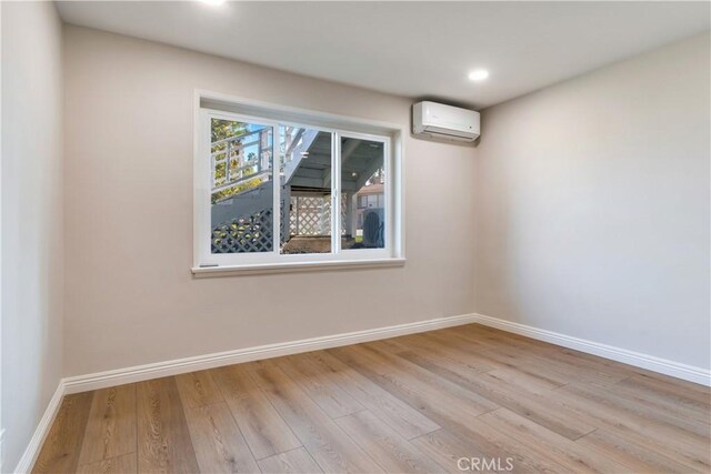 empty room featuring a wall unit AC and light hardwood / wood-style flooring