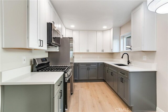 kitchen featuring light wood-type flooring, gray cabinetry, stainless steel appliances, sink, and white cabinets