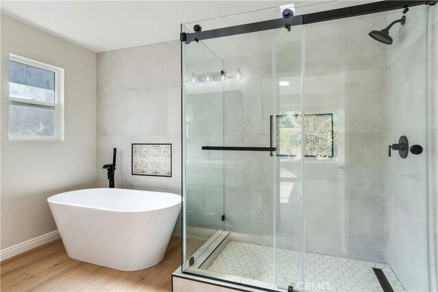 bathroom featuring separate shower and tub, a healthy amount of sunlight, and wood-type flooring