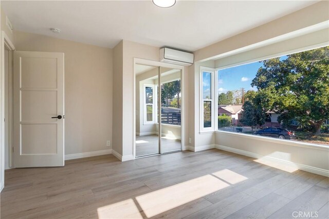 interior space with light wood-type flooring and a wall mounted AC