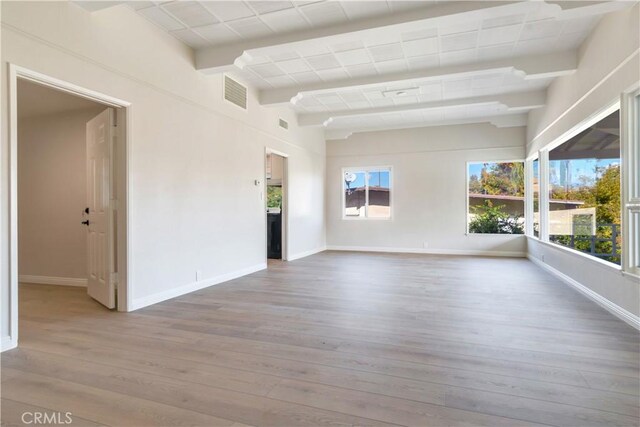 spare room featuring beam ceiling and hardwood / wood-style flooring