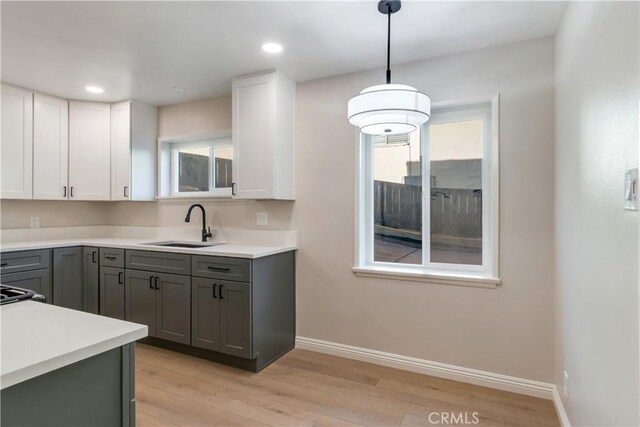 kitchen with gray cabinets, sink, white cabinets, and hanging light fixtures