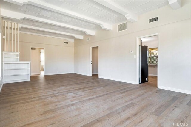 empty room featuring light hardwood / wood-style flooring and beamed ceiling