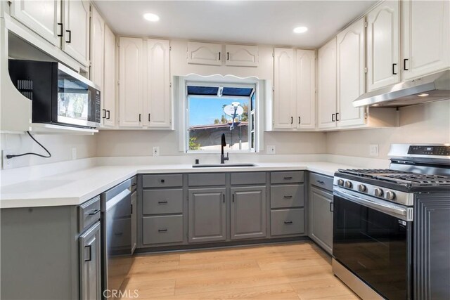 kitchen featuring white cabinets, gray cabinets, sink, and appliances with stainless steel finishes