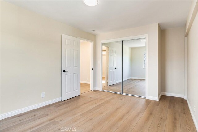 unfurnished bedroom featuring light wood-type flooring and a closet