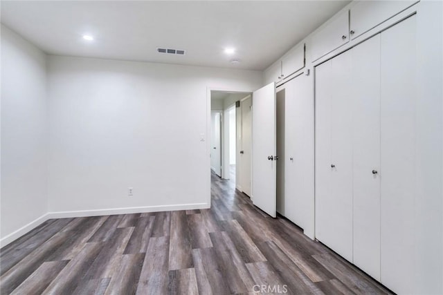 unfurnished bedroom with two closets and dark wood-type flooring