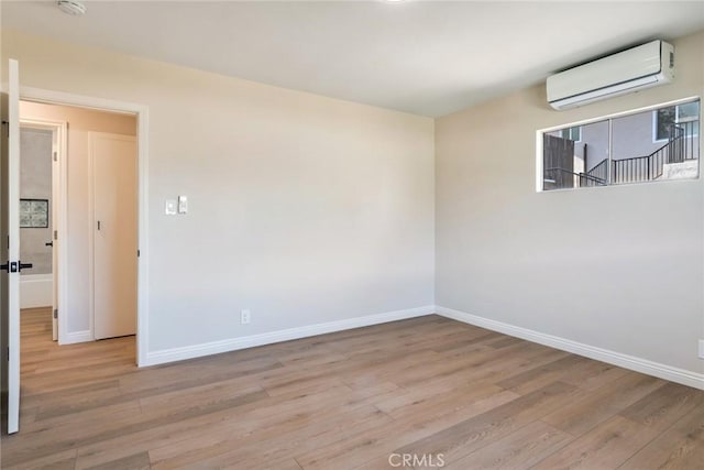 unfurnished room with a wall mounted air conditioner and light hardwood / wood-style floors