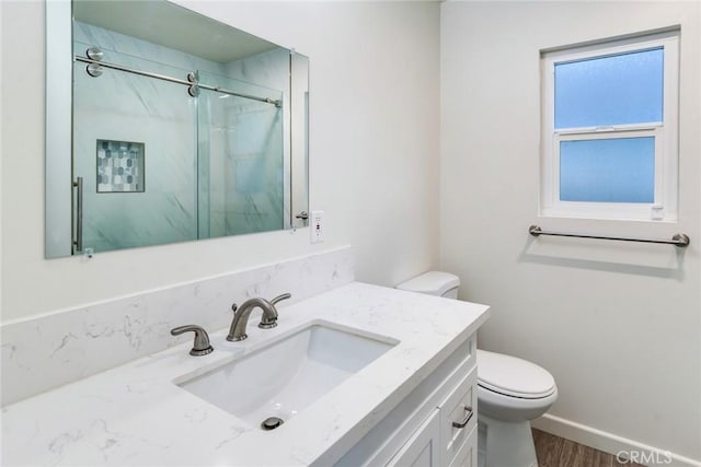 bathroom with hardwood / wood-style floors, vanity, toilet, and walk in shower