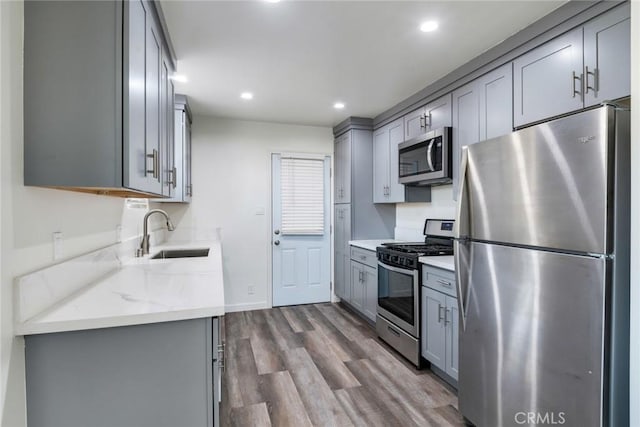 kitchen with gray cabinets, wood-type flooring, sink, and appliances with stainless steel finishes