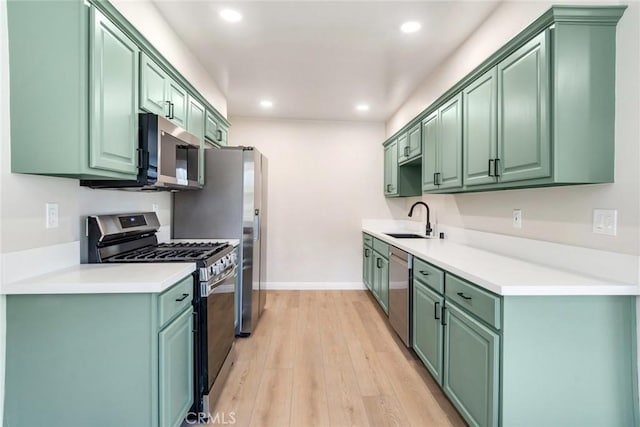 kitchen with stainless steel appliances, light hardwood / wood-style flooring, green cabinetry, and sink