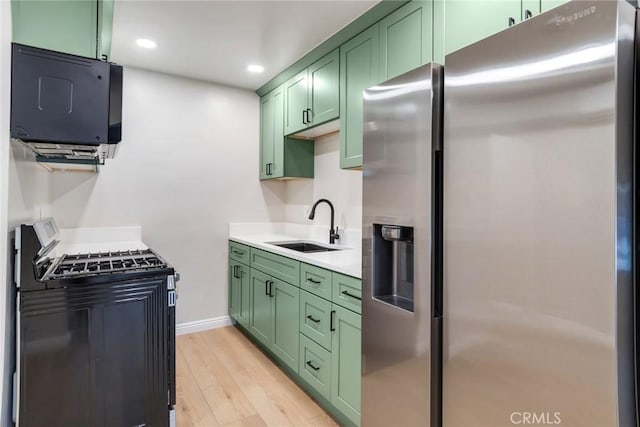 kitchen with gas range, sink, stainless steel fridge with ice dispenser, light hardwood / wood-style floors, and green cabinetry