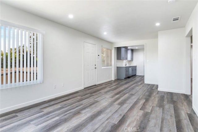 unfurnished living room featuring plenty of natural light, dark hardwood / wood-style floors, and sink