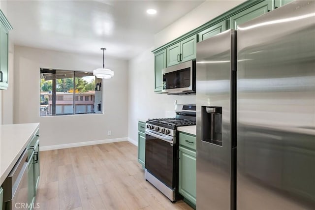 kitchen featuring appliances with stainless steel finishes, light wood-type flooring, green cabinetry, and pendant lighting