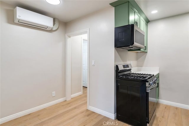 kitchen with black gas range, a wall mounted AC, light hardwood / wood-style floors, and green cabinetry