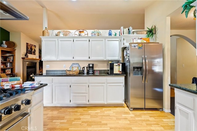 kitchen featuring white cabinets, dark stone counters, stainless steel refrigerator with ice dispenser, and light wood-type flooring