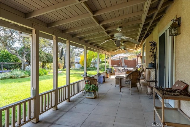 unfurnished sunroom featuring beamed ceiling and ceiling fan