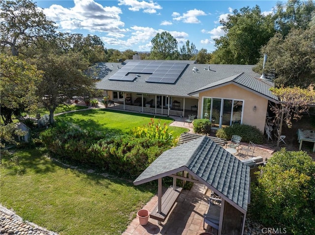 rear view of property with a lawn, solar panels, and a patio