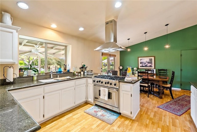 kitchen with white cabinetry, kitchen peninsula, luxury stove, light hardwood / wood-style floors, and island range hood