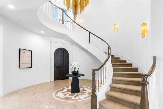 entryway featuring recessed lighting, a towering ceiling, baseboards, and stairs