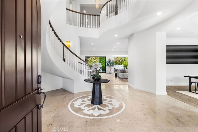 foyer entrance with recessed lighting, baseboards, a high ceiling, and stairs